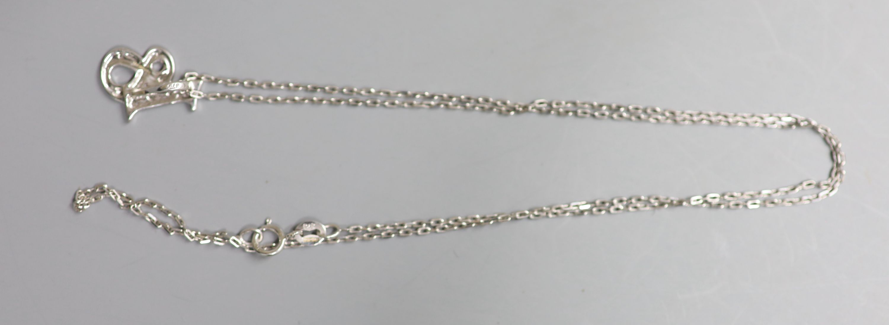 A modern 9ct white gold and diamond chip set 18 pendant, 14mm, on a 9ct white gold fine link chain, 43cm, gross 2.5 grams.